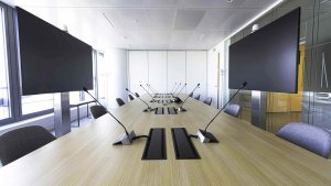 Photo de présentation de l'aménagement d'une grande salle de conférence équipée d'écrans et de micros lors de l'aménagement des bureaux professionnels de Saint-Gobain à Paris La Défense.