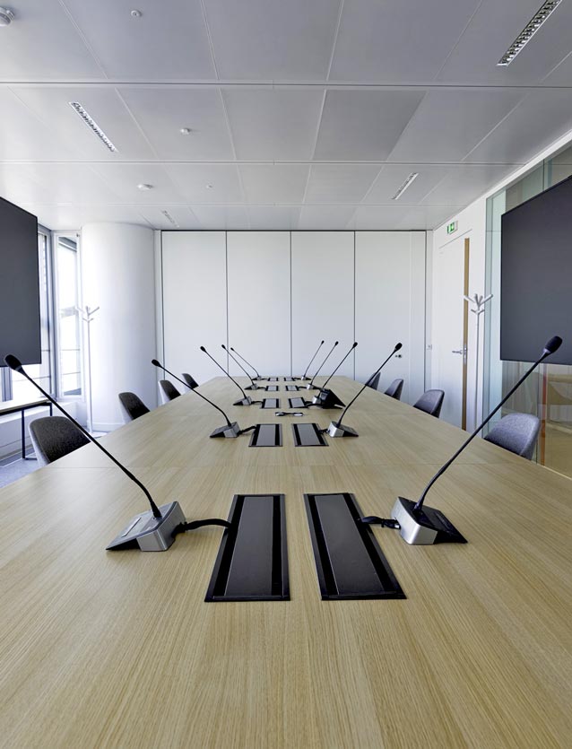 Photo de présentation de l'agencement d'une grande salle de conférences équipée d'une table électrifiée dans les bureaux de Saint Gobain à Paris La Défense
